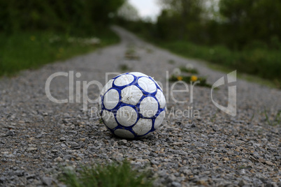 Old football ball lies on the road