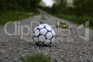 Old football ball lies on the road