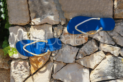 Sandals glued to a wall of stone