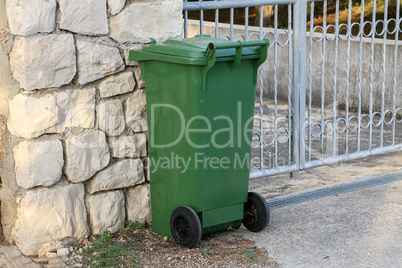 Green trash can stands at the gates