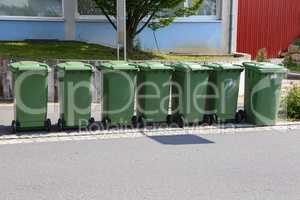 Green garbage cans are on the street