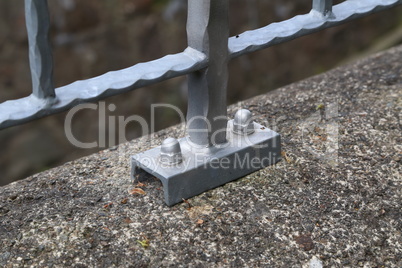 The metal fence is fixed on a concrete slab by means of bolts