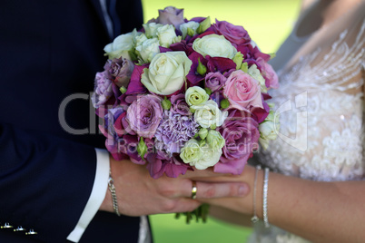 Bride and groom are holding a wedding bouquet