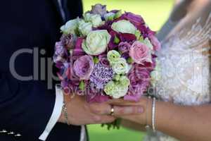 Bride and groom are holding a wedding bouquet
