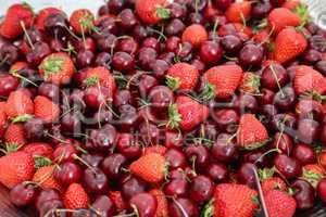 Ripe strawberries and cherries scattered on the table