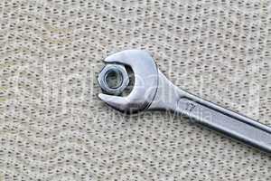 A wrench with a nut lie on the table