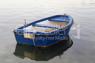 Blue fishing boat stands on a quiet lake