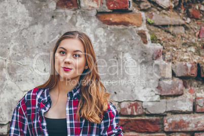 Beautiful girl is standing against brick wall