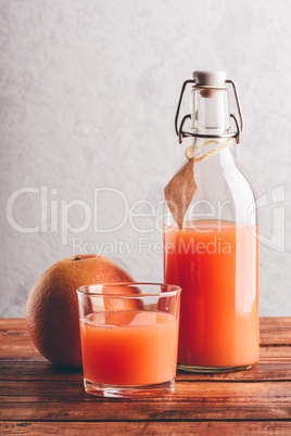 Bottle of grapefruit juice with glass and fruit