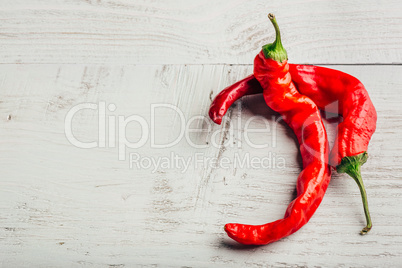 Two chili peppers over wooden background.