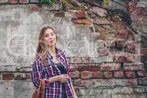 Beautiful girl is standing against brick wall