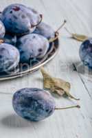 Plums on wooden surface with leaves