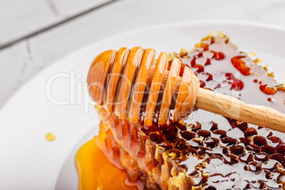 Honeycomb on plate with honey dipper