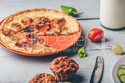 Frittata with muffins over light wooden background.