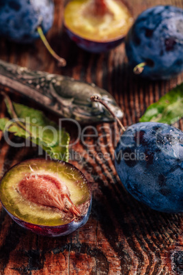 Ripe plums with leaves, water drops and knife