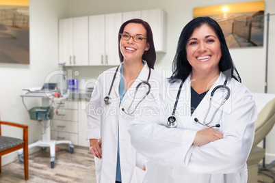 Hispanic and Caucasian Female Doctors Standing In Medical Office