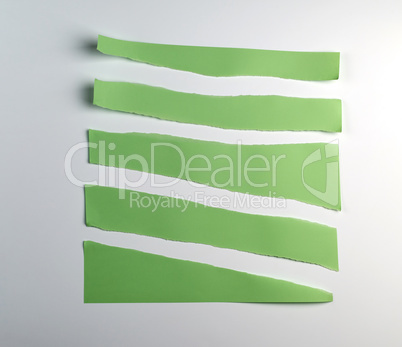 various torn pieces of green strips of paper on a white backgrou