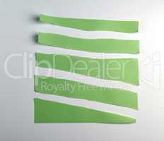 various torn pieces of green strips of paper on a white backgrou