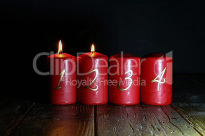 2.Advent. Red Advent candles stand on a wooden floor