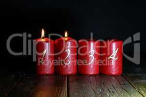 2.Advent. Red Advent candles stand on a wooden floor