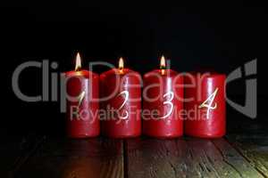 3.Advent. Red Advent candles stand on a wooden floor