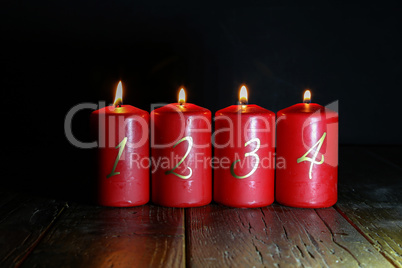 4.Advent. Red Advent candles stand on a wooden floor