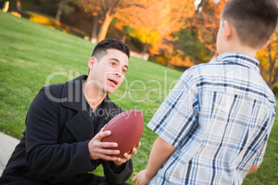 Hispanic Father Holding Football Teaching Young Boy