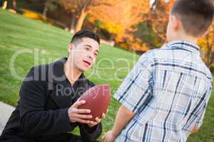 Hispanic Father Holding Football Teaching Young Boy