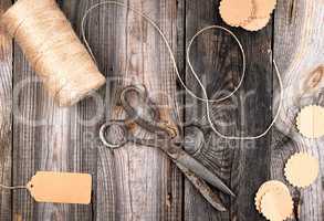 coil of brown rope, paper tags and old scissors on a gray wooden