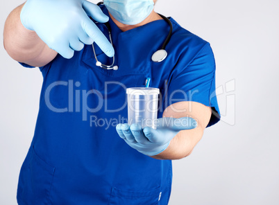 doctor in blue uniform and latex gloves is holding an empty plas