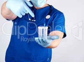 doctor in blue uniform and latex gloves is holding an empty plas