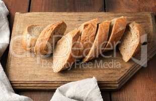 sliced rye flour baguette on a wooden cutting board