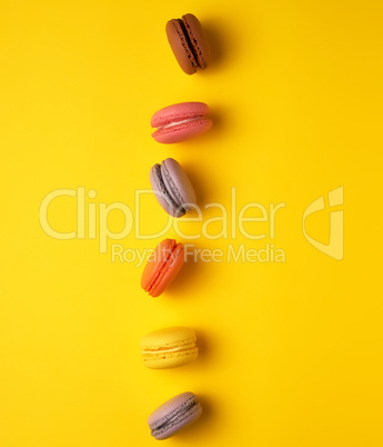 assortment of multi-colored baked round macarons on a yellow bac