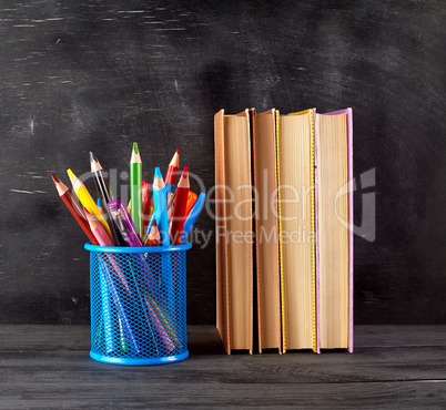 stack of books and a blue stationery glass with multi-colored wo