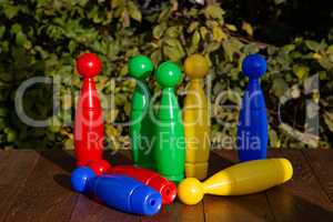 Colorful plastic toy bowling pins on wooden floor