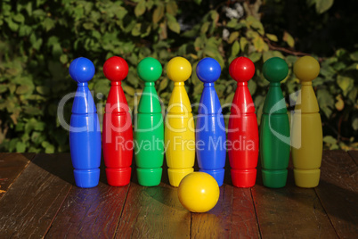 Colorful plastic toy bowling pins on wooden floor