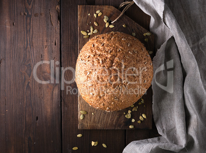 baked round rye bread with sunflower seeds on a gray textile nap