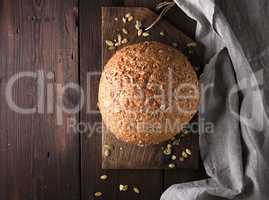 baked round rye bread with sunflower seeds on a gray textile nap