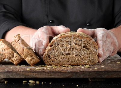 chef in black uniform keeps cut off a piece of bread baked from