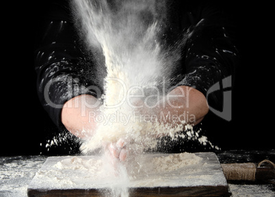 chef in black uniform sprinkles white wheat flour in different d