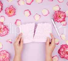 two hands hold an empty pink sheet torn from a notebook