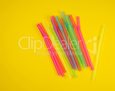 multicolored plastic cocktail tubes on a yellow background