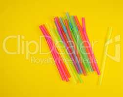 multicolored plastic cocktail tubes on a yellow background