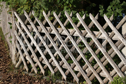 Wooden wattle fence in a garden near a rural house