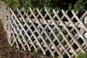 Wooden wattle fence in a garden near a rural house