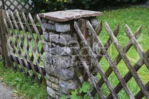 Wooden wattle fence in a garden near a rural house