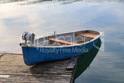 Blue fishing boat stands on a quiet lake