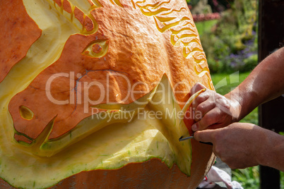 Mans hands close-up carve pumpkinat the autumn holiday