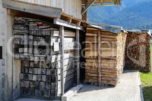 Dry wood piled under a canopy near the house