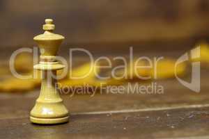 White Queen chess piece on blurred brown background